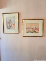 Both framed paintings hung side by side on wall