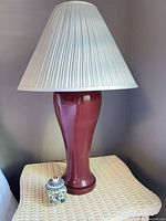 Full view of lamp with shade and decorative jar on table