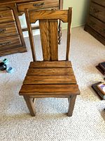 Front view of oak side chair showing slatted seat and paneled backrest
