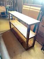 Full view of wicker rattan console table showing overall structure and three shelves
