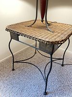 Full view of accent table showing wicker top and iron frame