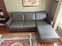 front view of gray leather sectional sofa showing three seat cushions and chaise