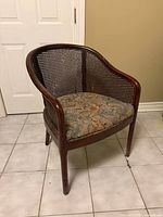 Front view of cane barrel-back chair showing overall design and upholstery