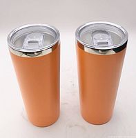 pair of orange stainless steel tumblers with lids