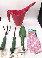 All five garden items grouped: watering can, hand cultivator, weeder, trowel, gloves