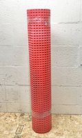 Front view of full roll of red dimpled membrane standing upright, shrink-wrapped