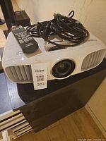 Projector top with remote and cables visible