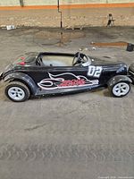 Side view of black go-kart showing full body, number 02 and Prowl Around decal