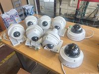 Ten white PoE security cameras on bench