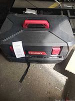 Closed Husky hard plastic case with red handle and latches