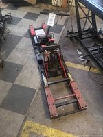 Full view of one hydraulic motorcycle lift jack showing frame, bottle jack, wheels, handle