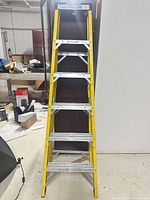Full front view of closed 6 ft yellow fiberglass step ladder showing five steps