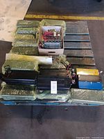 Pallet showing entire assortment of green wrapped packs, black housings, blue and yellow modules, and box of cell arrays