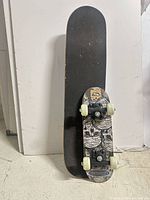 Black grip skateboard showing deck, trucks, wheels and underside graphic