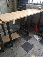 Full view of workbench showing wood top, metal legs, lower shelf