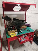 Full view of red metal workbench with overhead hutch, drawers and hardware on surface