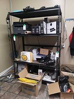 Full view of assembled four-shelf black steel storage rack holding miscellaneous items (not included)