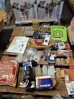Wide view of entire lot on pallets showing auto part boxes, glassware, wooden bowl, textiles, tray, framed print and accessories