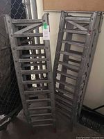 Front view of both folded aluminum loading ramps leaning against wall