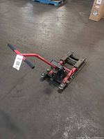 Full view of jack on shop floor showing handle, frame, casters