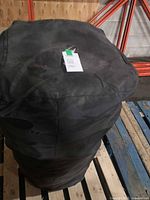 Rolled mattress in black carry bag standing on pallet