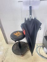 Stool and closed umbrella against wall