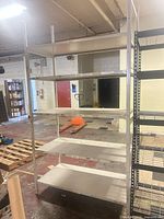 Full view of assembled white metal shelving unit showing five shelves