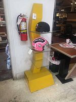 Full view of yellow painted metal display stand with three glass shelves