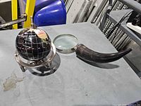 Globe on tripod stand beside horn-handled magnifier on table