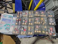 Overview of 19 Nendoroid-style figures in trays plus some box sleeves