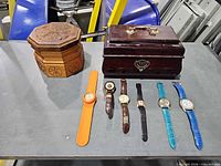 Overview of lot with two wooden boxes and seven wrist watches on table