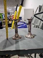 Pair of silver plated candlesticks with measuring tape showing 7 in height