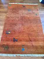 Full view of orange area rug showing motifs and fringe