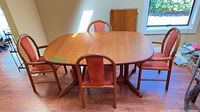 Full view of teak dining table with four chairs and leaf inserted