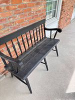 Front angled view of entire black wooden bench on porch