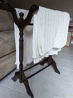 Side view of dark wood blanket rack holding two cream blankets