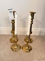 Front and rear view showing two sizes of brass candlesticks with candles