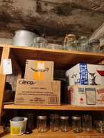 Shelving with aluminum stock pot, cardboard boxes of jars, loose quart jars and smaller jars