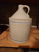 Front view of cream glazed stoneware jug with blue bands and handle