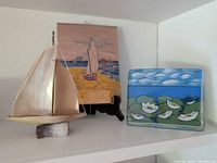 glass block art beside sailboat sculpture and small painting