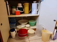 Cabinet overview showing pitchers, thermoses, storage containers