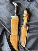 Both knives in their leather sheaths side by side