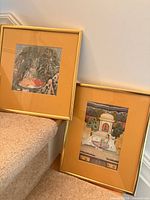 Both framed prints leaning on staircase showing relative sizes and frames
