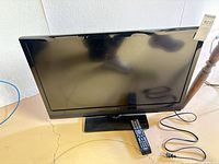 Front view of Insignia television with screen off and remote on base