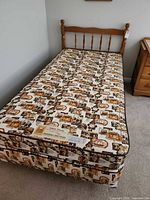 Full view of assembled twin bed showing maple headboard, mattress, boxspring