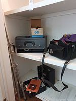 Shelf view showing projector cases, camera bag, film box, tripod screen stand