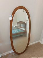Front view of oval wood-framed mirror leaning against wall