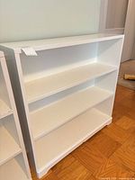 Front view of white painted wood bookshelf with three shelves
