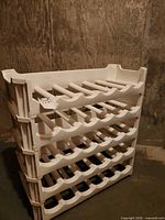 Front angled view showing all five tiers and overall condition of the white plastic wine rack
