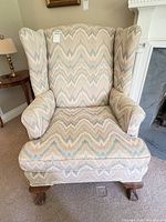 Front view of upholstered wing chair showing flame stitch fabric and carved legs